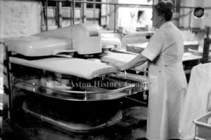 Old photo of worker using a steam press in Aston Laundry.