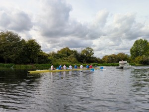 Rowing Eight watched by a Heron, with accompaning motor boat